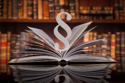 Symbolbild Gesetz - Geöffnetes Buch mit Paragrafzeichen
